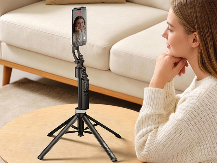 A young woman posing in front of a smartphone mounted on a mini desktop tripod.