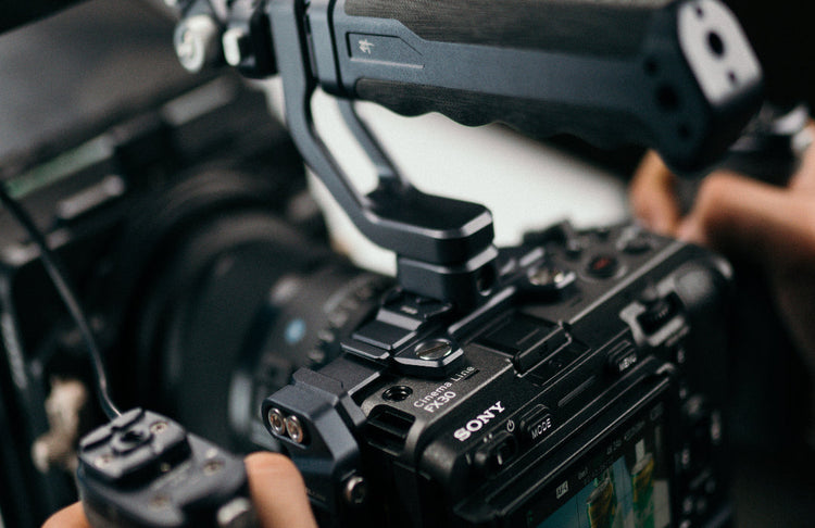 Sony Cinema Line FX30 camera mounted in a professional camera cage with top handle, held by a videographer