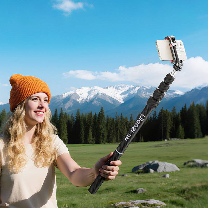 Woman using Ulanzi T230 selfie stick outdoors with mountains.