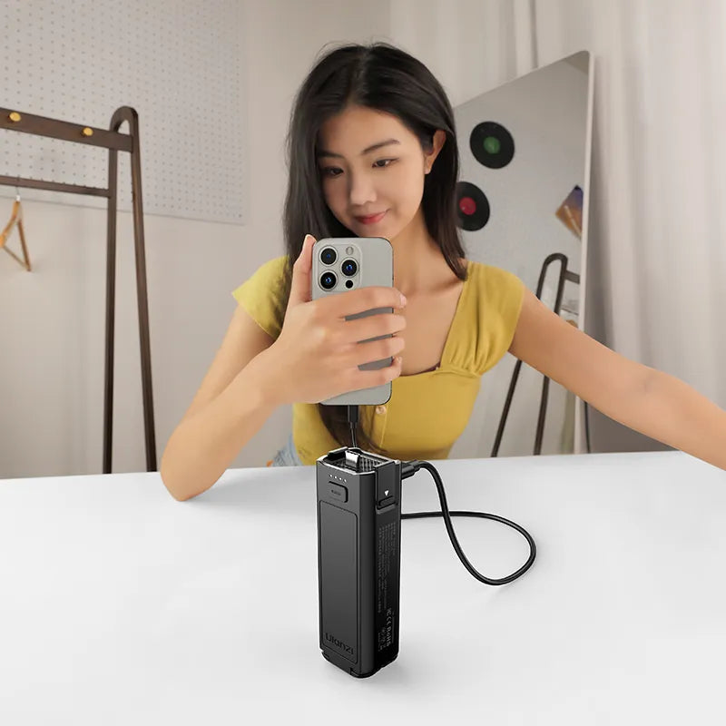 Woman using Ulanzi PK-12 Mini Quadpod Battery Handle for Pocket 3, filming with phone, black charger.