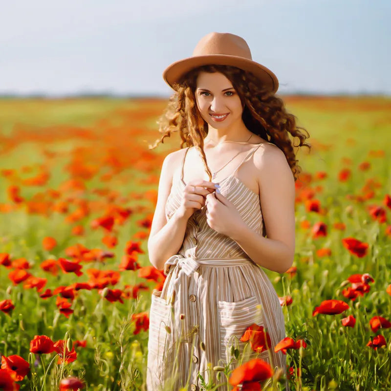 Young woman in dress and hat smiles in poppy field, Ulanzi product lifestyle shot.