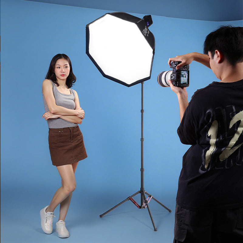 Photographer using Ulanzi T230 light stand with softbox in studio.