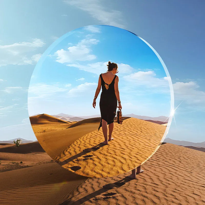 Woman in black dress walking on desert sand dune, creative composition, circular frame.