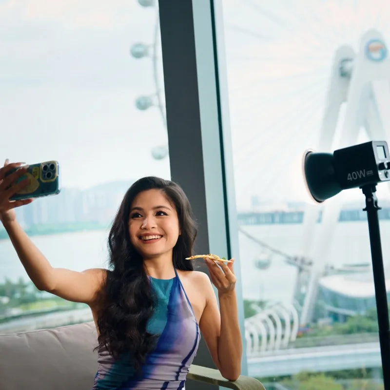 Woman with Ulanzi L023 40W Pro LED Video Light, taking a selfie while enjoying pizza.