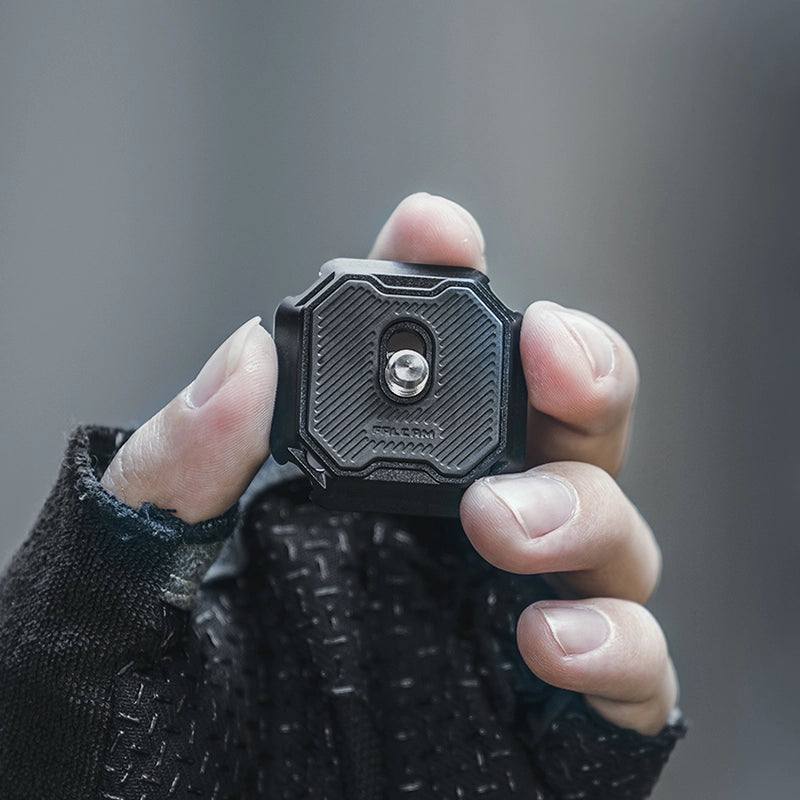 Ulanzi Falcam F38 Multi-hole Quick Release Base held in hand, black aluminum alloy design.