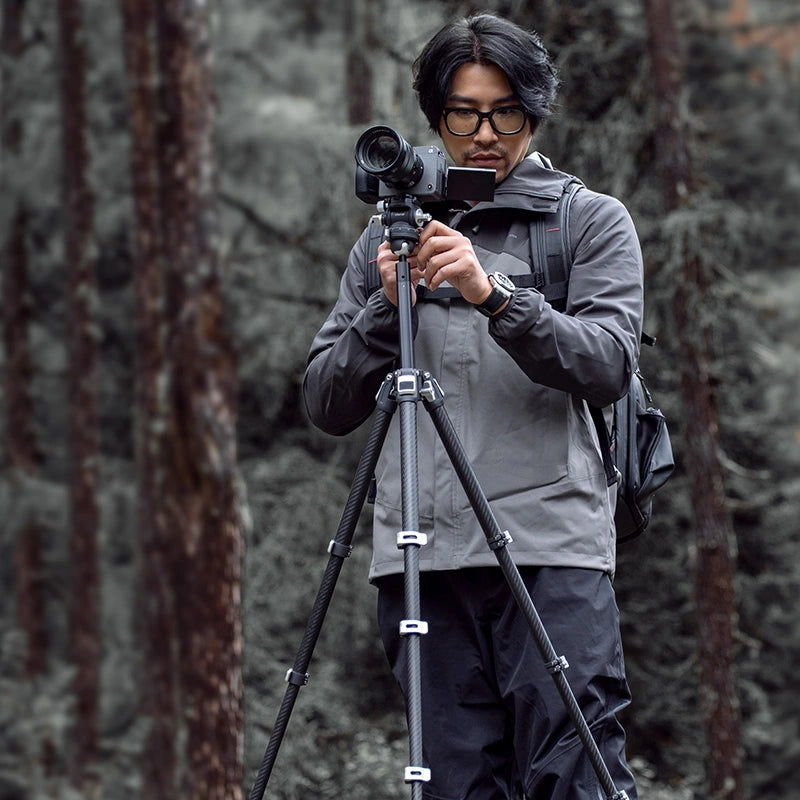 Ulanzi TT09 Carbon Fiber Travel Tripod in use by photographer outdoors, with camera and backpack.