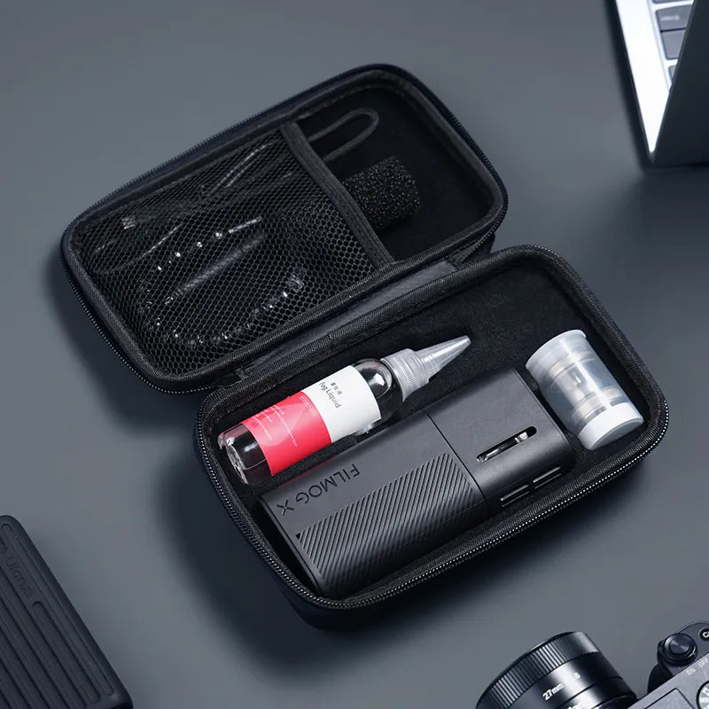An open carrying case displaying a FILMOG X portable fog machine, liquid bottle, and accessories neatly organized inside.