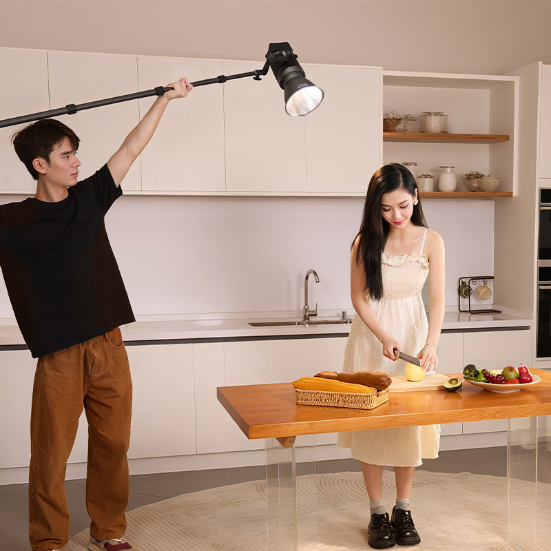 Man holding light for woman cooking in kitchen.