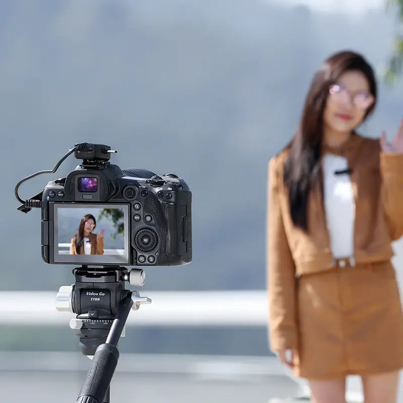 Woman with wireless lavalier microphone recording video with camera setup.