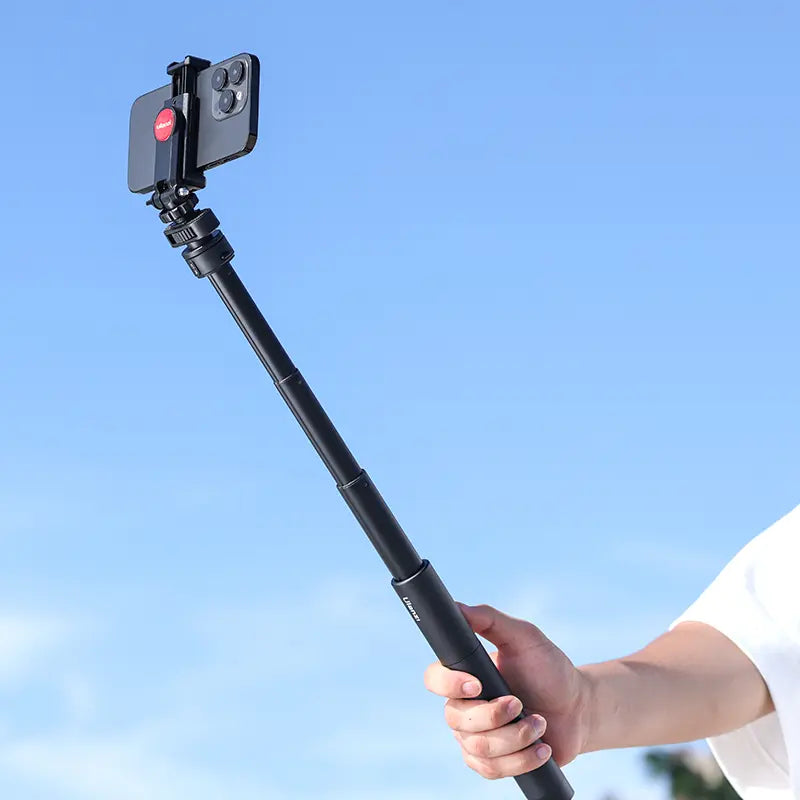 Ulanzi Go-Quick II Magnetic Quick Release Adapter with phone in hand, black, against blue sky.