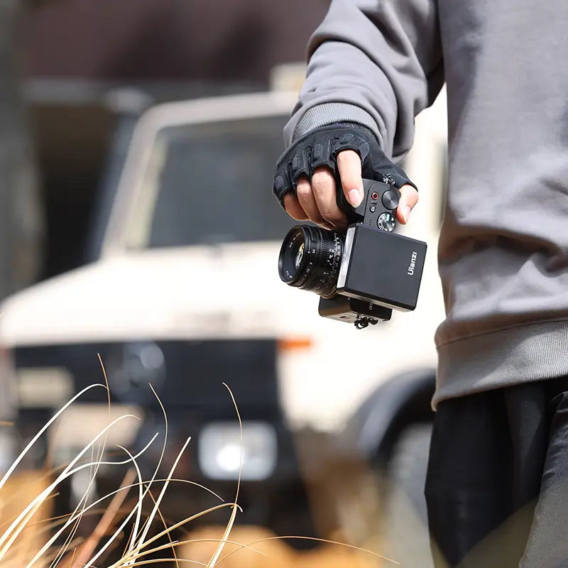Ulanzi F12 Mini Camera Flash Speedlite in hand, ready for photography outdoors.