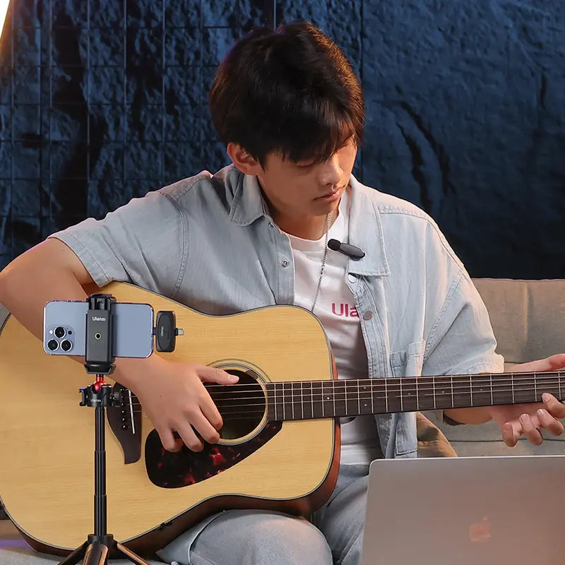 Ulanzi V6 wireless microphone setup for recording; man playing guitar with phone on tripod.