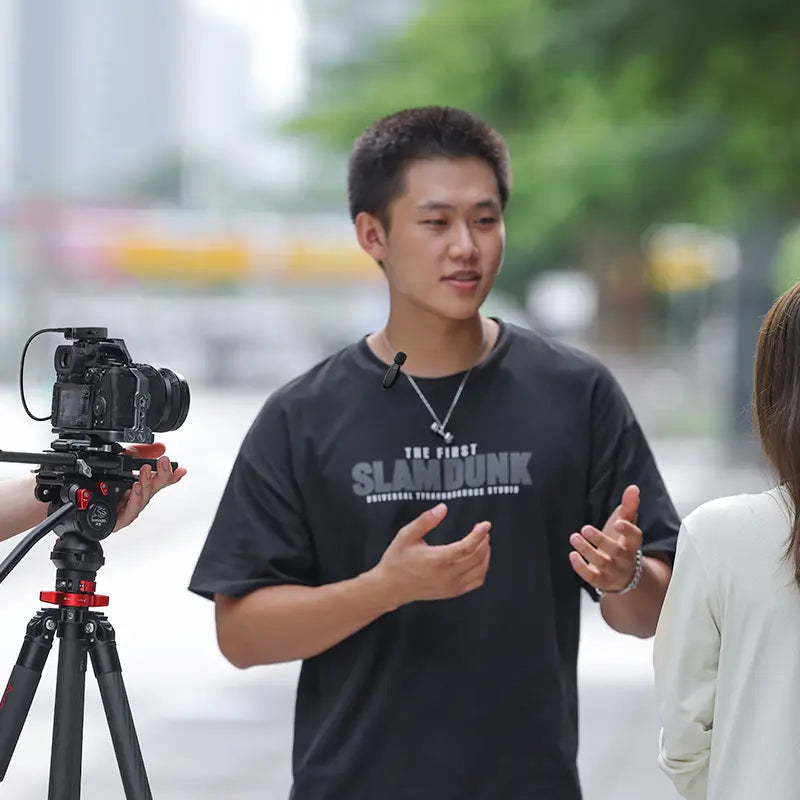Man using Ulanzi V6 wireless microphone during video recording with DSLR camera on tripod.