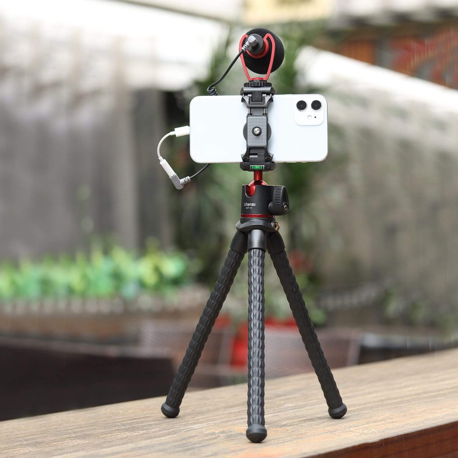 Ulanzi MT-11 Octopus Tripod holding smartphone with microphone, on wooden surface.