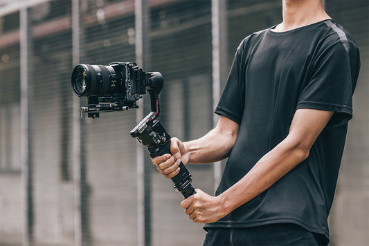 Person holding a camera mounted on a stabilizer gimbal.