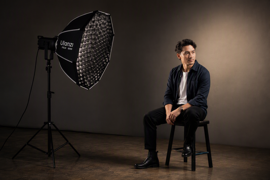 Octagonal softbox with honeycomb grid lighting a portrait subject in a compact studio while the nearby background remains comparatively dark.