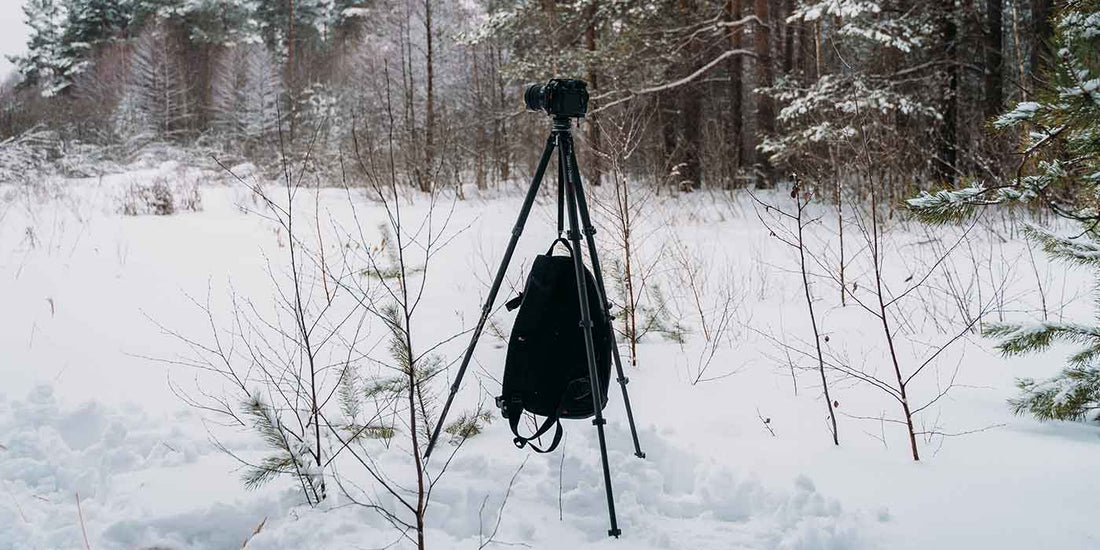 Ulanzi carbon fiber tripod setup in a snowy forest with a camera backpack hanging from the center column for stability