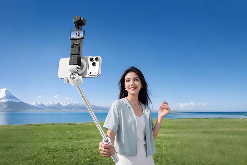 Stabilized vlogging setup featuring a handheld gimbal camera and smartphone on a selfie stick tripod, used for travel content creation outdoors