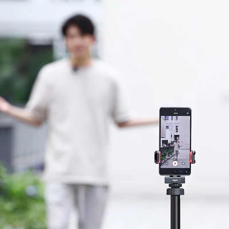 Recording on smartphone with Ulanzi tripod, man gesturing in blurred background.