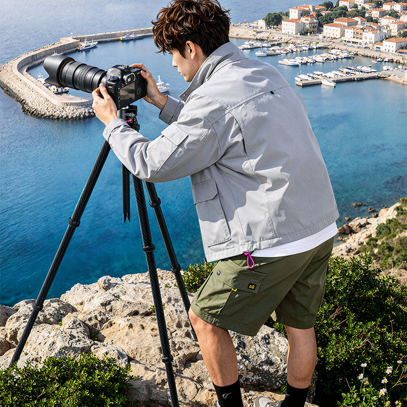 Photographer adjusting a camera on a carbon fiber tripod overlooking a coastal harbor