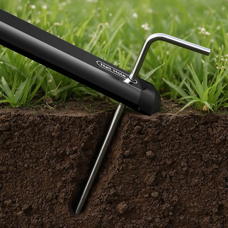 A tripod leg being anchored into the ground with a metal stake.