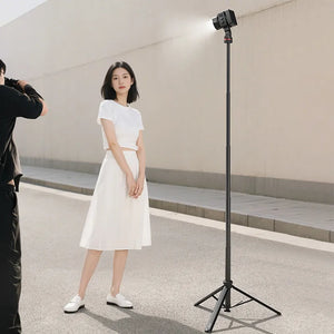 A photographer taking a picture of a woman posing, illuminated by a light on a stand.