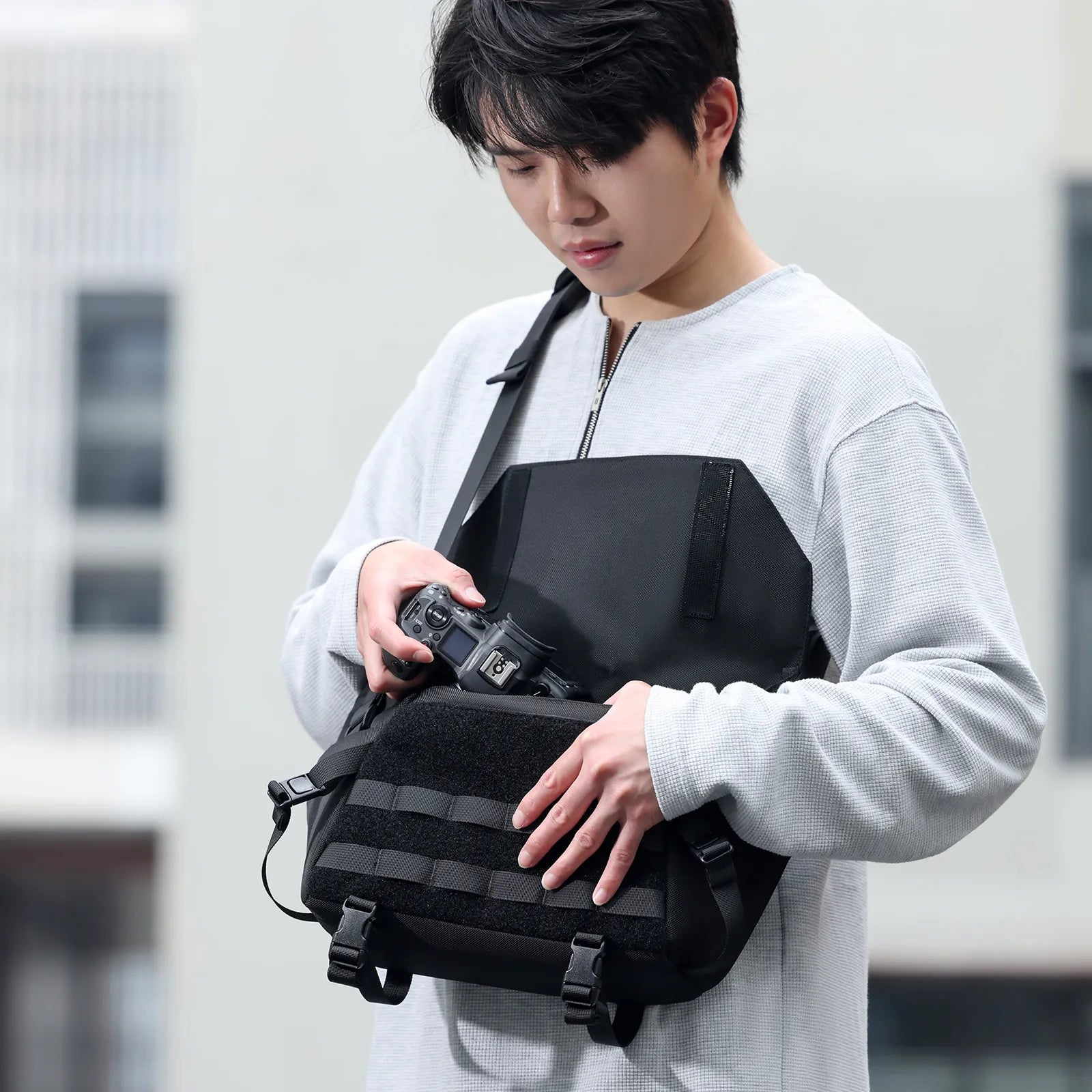 Person adjusting camera in Ulanzi BC08 sling bag worn crossbody.