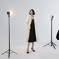 Woman posing for a photoshoot, illuminated by two studio lights on tripods.