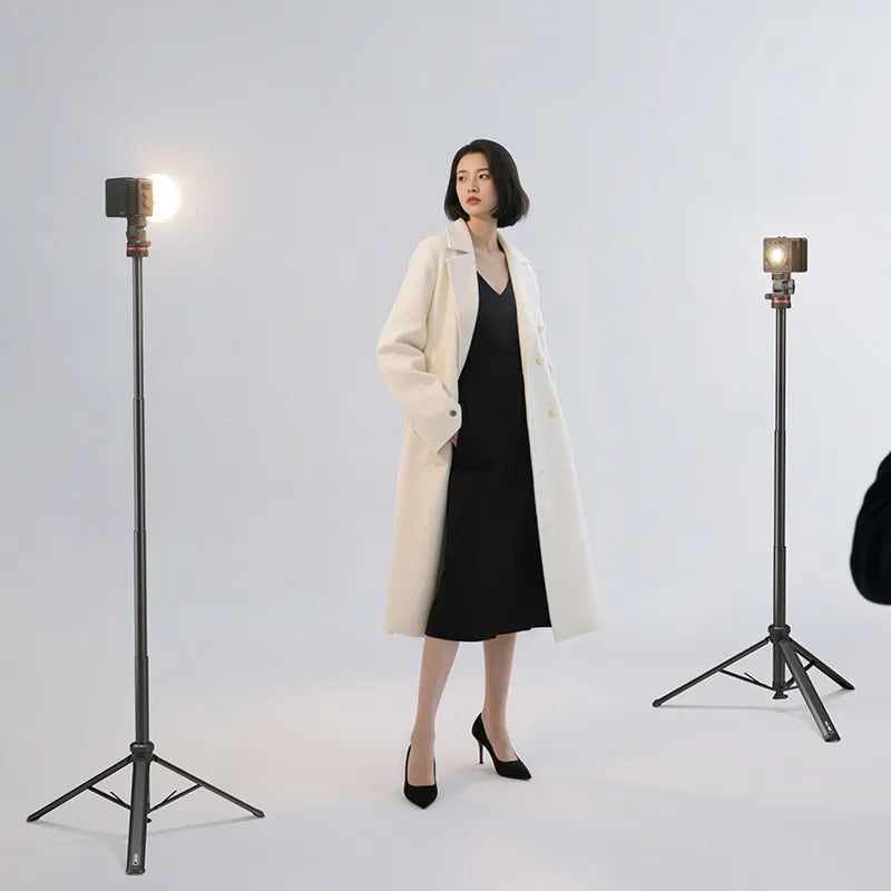 Woman posing for a photoshoot, illuminated by two studio lights on tripods.