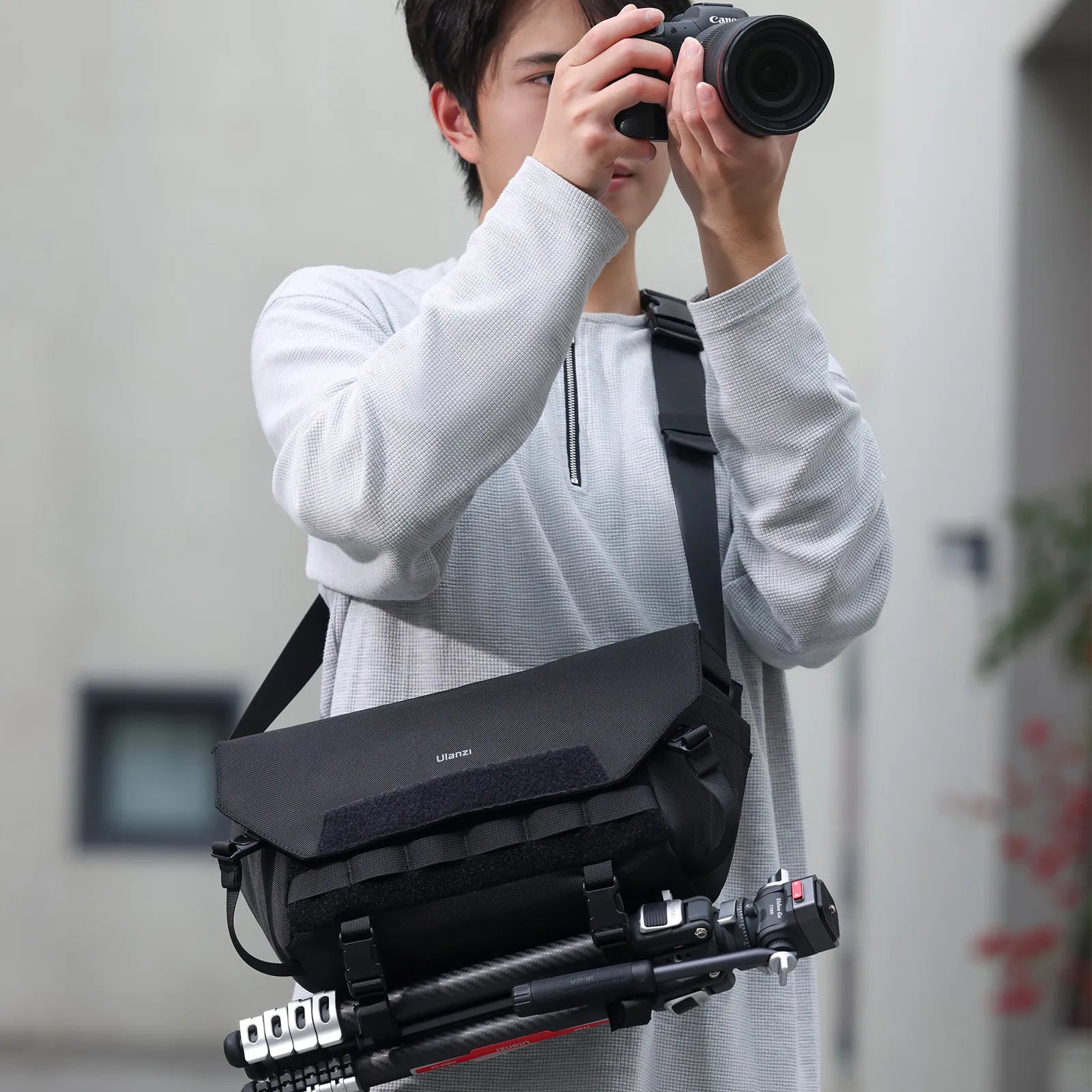 User holding camera with Ulanzi BC08 sling bag worn crossbody.