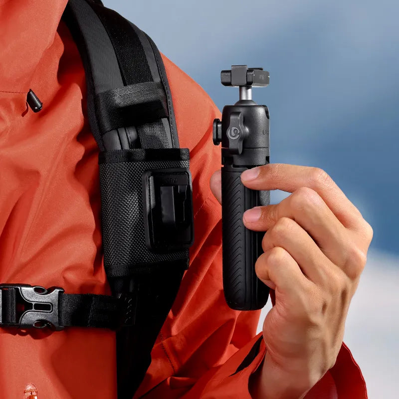 Close-up of a hand adjusting the Ulanzi MT66 tripod attached to a backpack strap, showing the quick-release mechanism.