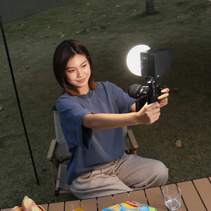 Woman using Ulanzi EC65 Bi-Color LED light for selfie, highlighting portable video lighting.