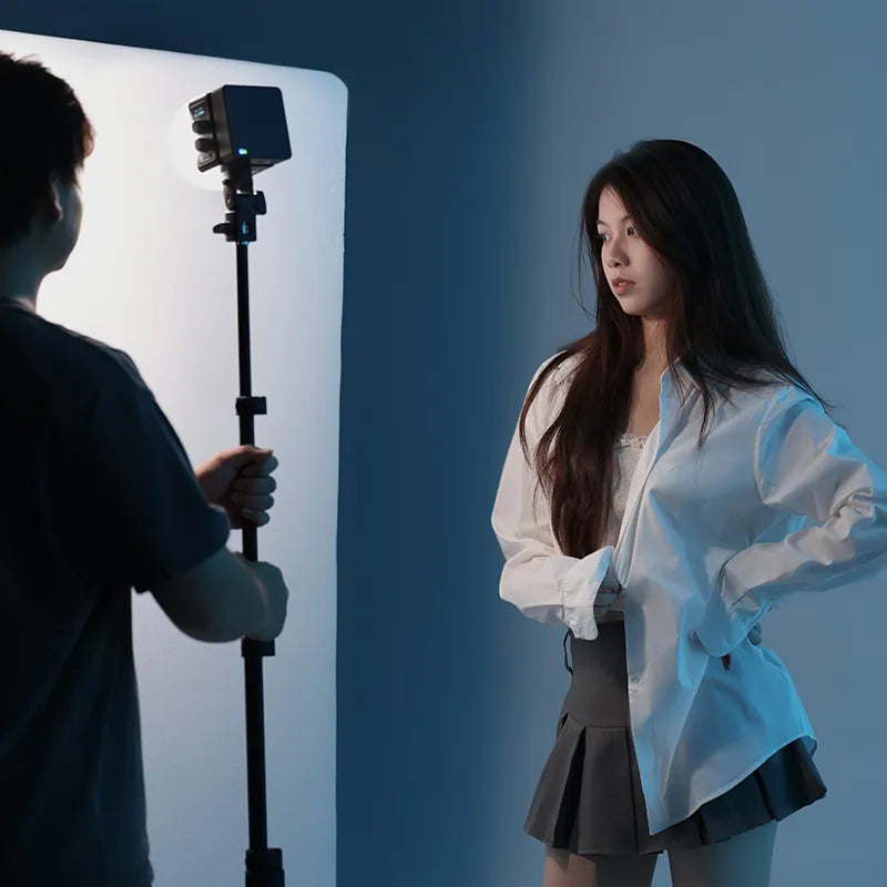 Compact cube light casting dramatic shadows on model in minimalist fashion photoshoot.