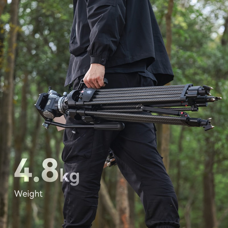Person carrying Ulanzi VideoFast Heavy Duty Tripod Kit in a forest setting.