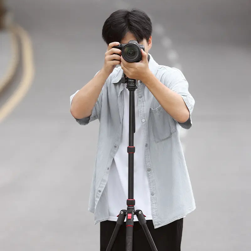 Person using Ulanzi TT31 tripod with camera outdoors, demonstrating portability.