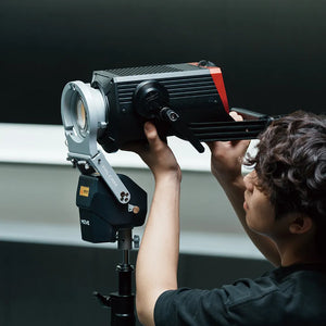 A technician adjusting a FALCAM MOVE LED light mounted on a stand, designed for precise and remote-controlled lighting setups.