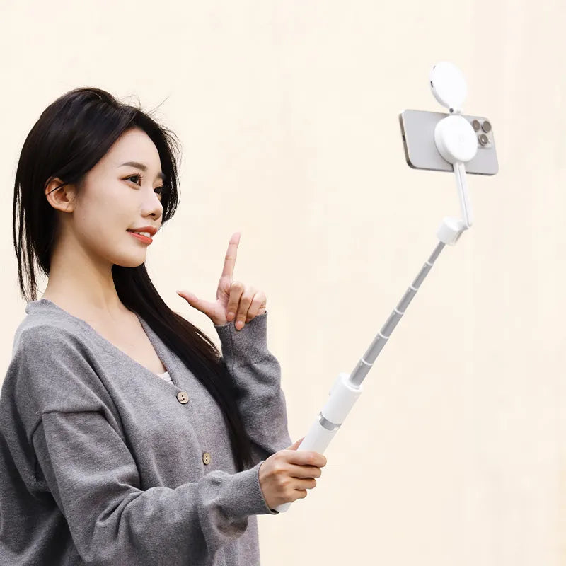 Woman demonstrating Ulanzi MG-003 selfie stick tripod with smartphone outdoors