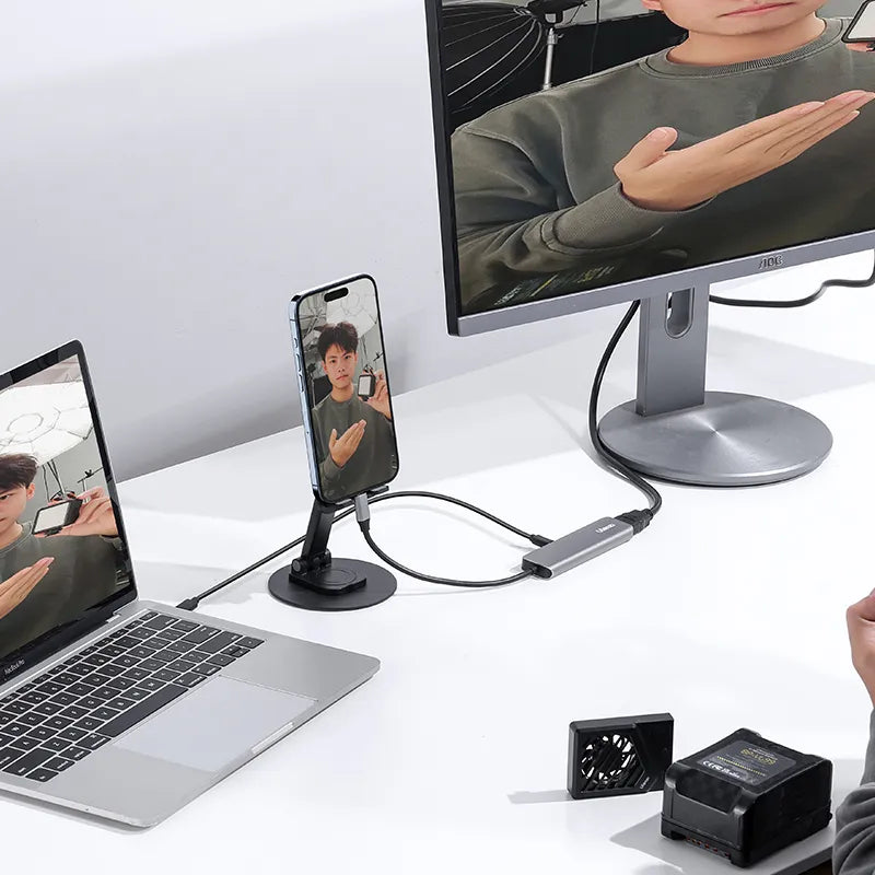 User demonstrating Ulanzi C060 video capture card connected to laptop and monitor.