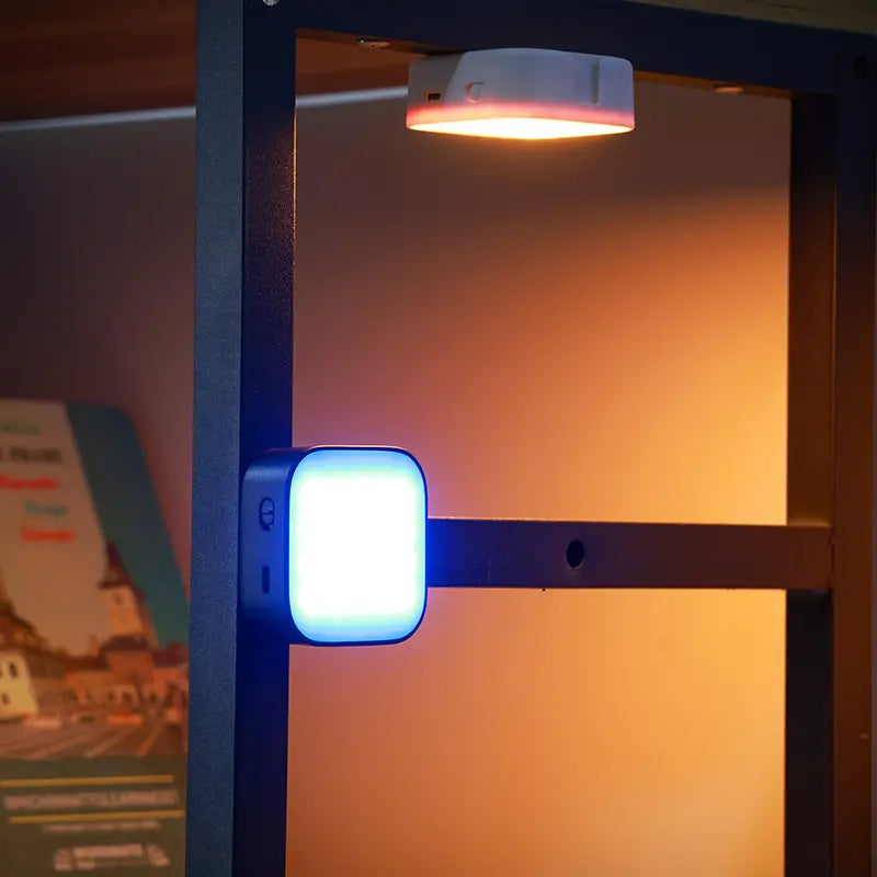 Ulanzi U60 compact RGB LED video light attached to a black shelf emitting blue light.