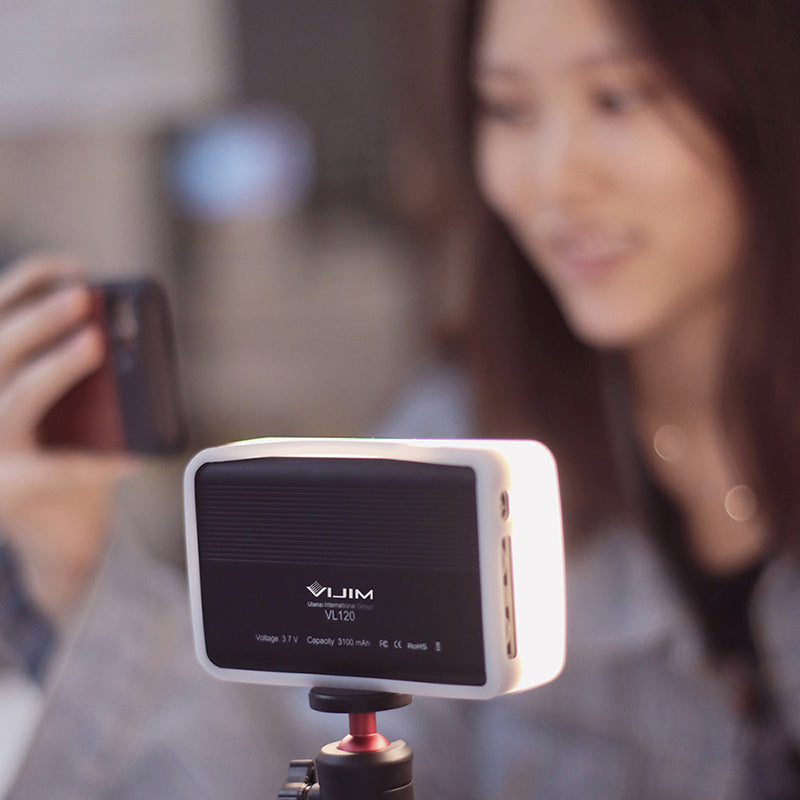 Ulanzi VIJIM VL120 Bi-Color LED Video Light enhancing photography with a woman using a smartphone.